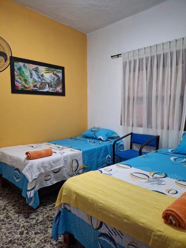 a room with two beds with blue and yellow at Casa avemaría in Cali