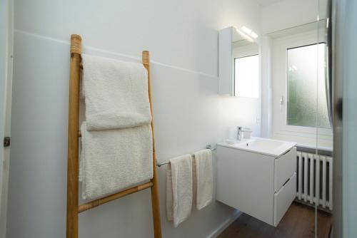 a white bathroom with a sink and a mirror at Maraini Deluxe Apartment - free parking in Massagno