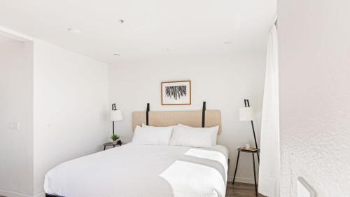 a white bedroom with a bed with white sheets and pillows at 2 Coastal Studios at Cayucus Beach Access Ocean Views in Cayucos