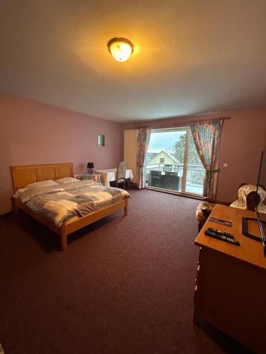 ein Schlafzimmer mit einem Bett und einem großen Fenster in der Unterkunft Aux Deux Clefs in Petersbach