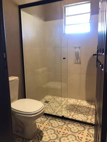 a bathroom with a toilet and a glass shower at Chalé Casa da Pedra in Cunha