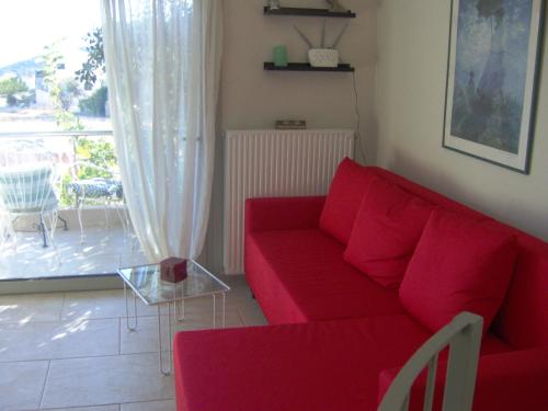 a living room with a red couch and a patio at Sunset at Cape Sounio in Sounio