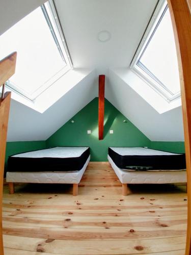 two beds in a room with green walls and skylights at La Grange de Pépé in Biltzheim