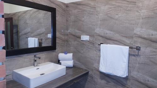 a bathroom with a sink and a mirror and towels at Orion Blue Hotel in Dombagahawatta