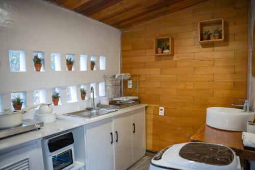 a kitchen with white cabinets and a sink and wooden walls at tinys house in Lạc Dương