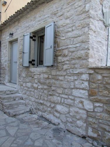 a stone building with two windows and a stone wall at Lovely in Lákka