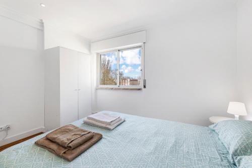 a white bedroom with a bed with a window at AGUALVA HAPPY APARTMENT in Paiõis