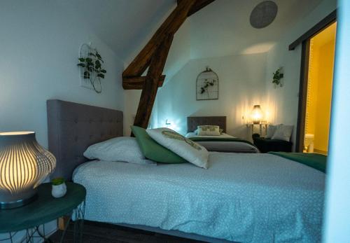 a bedroom with two beds and a table with a lamp at Chouette Nuit in Thenay