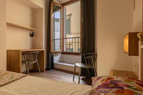 Schlafzimmer mit einem Bett und einem Fenster mit einer Bank in der Unterkunft Hostel Archi Rossi in Florenz