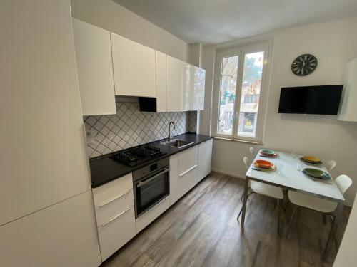 een keuken met witte kasten, een tafel en een wastafel bij La Casa Sul Viale in Iesi
