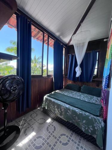a bedroom with a bed with blue curtains and a window at Casa na Floresta in Itacaré
