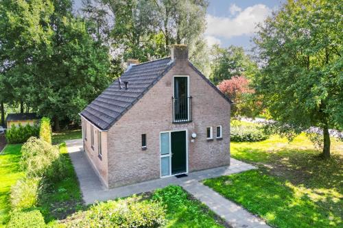 a small brick house with a green door at 5 - Person Forest 239 Sauna Bungalow in Ewijk