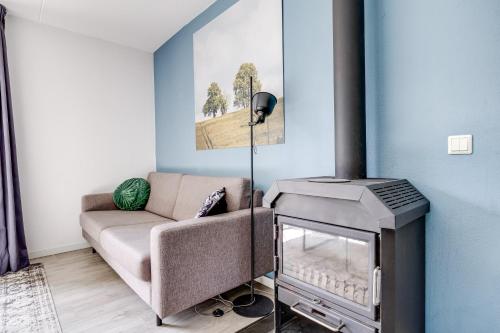 a living room with a couch and a stove at 5 - Person Forest 239 Sauna Bungalow in Ewijk