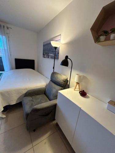 a bedroom with a bed and a chair and a lamp at Studio a 3 mn à pied des thermes in Balaruc-les-Bains