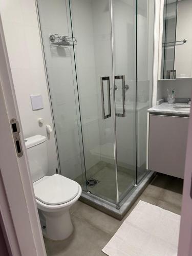 a bathroom with a toilet and a glass shower at Studio perto Shopping Estação com Piscina interna aquecida, Academia e Terraço Lindo pôr do Sol in Curitiba