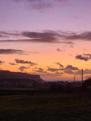 a sunset over a field with mountains in the background at The Cottage - Fairwinds in Doolin