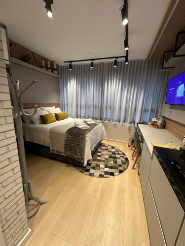 a bedroom with a bed and a flat screen tv at Studio perto Shopping Estação com Piscina interna aquecida, Academia e Terraço Lindo pôr do Sol in Curitiba