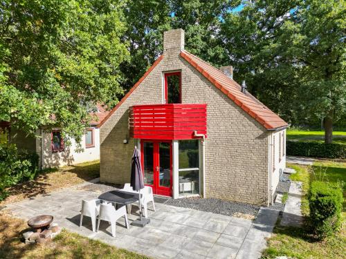 a small brick house with a red window and chairs at 6 - Persons Lakeside 61 Bungalow in Ewijk