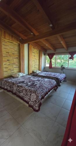 two beds in a large room with wooden ceilings at Casa El Limón in Zihuatanejo