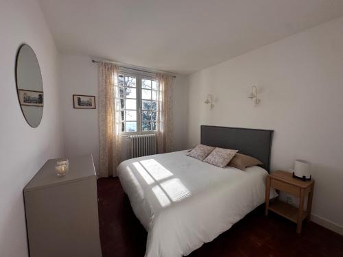 a bedroom with a white bed and a window at LES HAUTS DE TREMOLAT in Trémolat