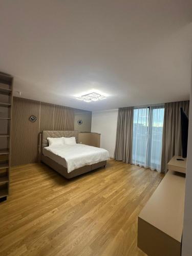 a bedroom with a white bed and wooden floors at KNIGHT RESORT Villa & Rooms in Voluntari