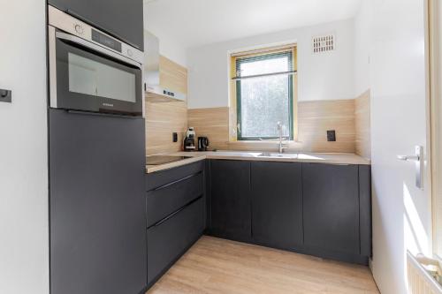 a kitchen with black cabinets and a sink at 6 - Persoons Forest 151 Bungalow in Ewijk
