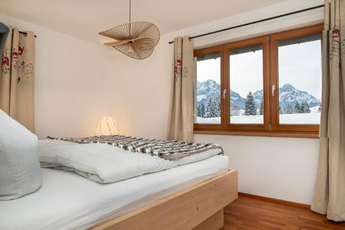 a bedroom with a bed and a window with mountains at Mazot Ferienhaus Kleinwalsertal in Riezlern