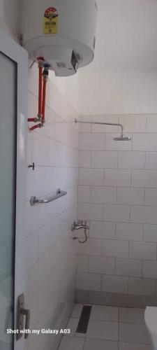 un bagno con una doccia piastrellata bianca con un tubo rosso di Tendaba Camp a Tendaba