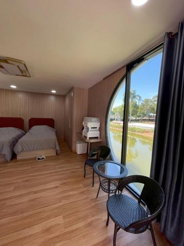 a bedroom with a bed and a table and a window at The Lakefront Collective in Buriram, Thailand in Ban Nong Muang