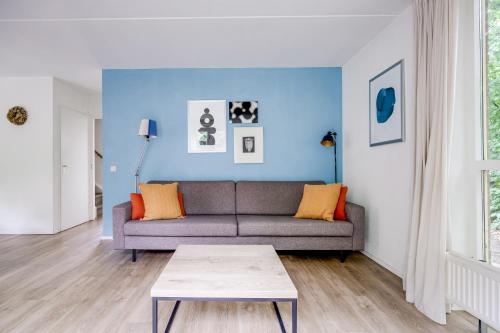 a living room with a couch and a blue wall at 6 - Persoons Forest 209 Bungalow in Ewijk