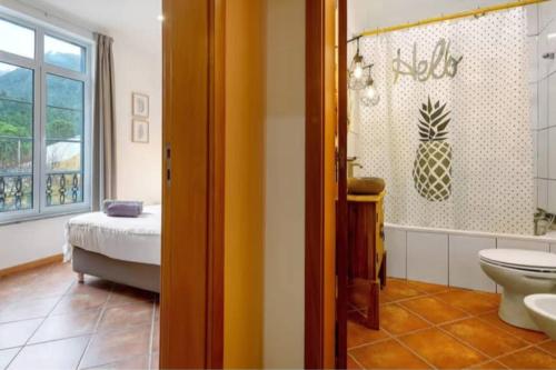 a bathroom with a toilet and a bed and a window at House Bali Furnas in Furnas