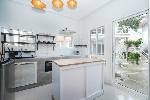 a kitchen with white walls and a large window at The One Cozy, Phuket in Chalong