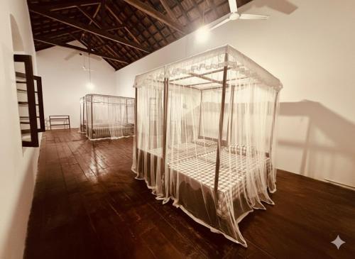 a room with four beds with nets on them at Charlotte's Coral Breeze - A Colonial Seaside Bungalow in Hikkaduwa
