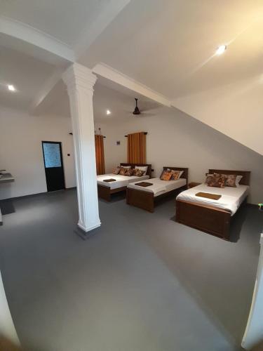 a large room with two beds and a column at Hiri Dudes Villa in Dickwella