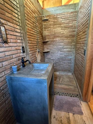 a bathroom with a sink and a brick wall at KAO Cabin in Brisas de Zicatela