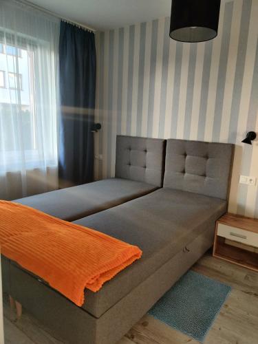 a bed with an orange blanket on it in a room at Apartament Charlie in Darlowko