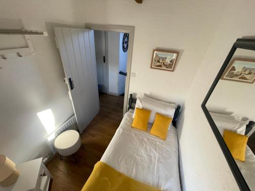 a small room with a bed with yellow pillows at Court Cottage - cosy traditional cottage near lovely beaches in Kingsbridge