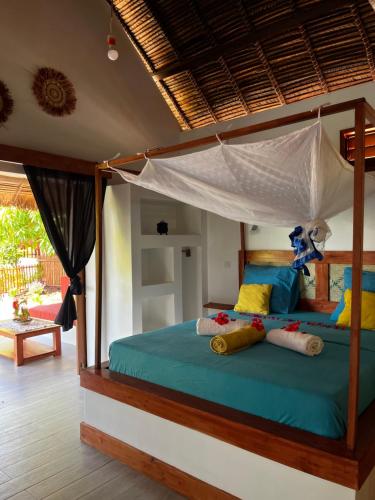 a bedroom with a canopy bed with colorful pillows at Bungalow Maniry Andilana in Andilana