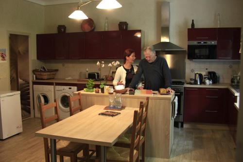 a man and a woman preparing food in a kitchen at Chambres d'Hôtes La Maison Blanche in Lorp Sentaraille