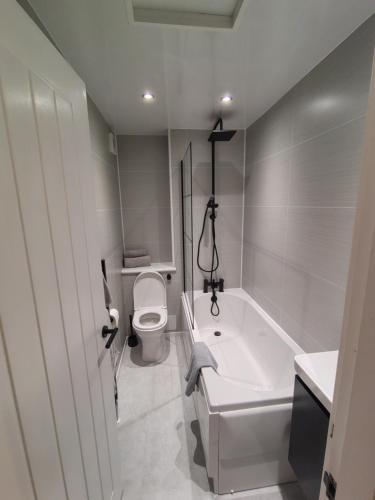 a white bathroom with a toilet and a bath tub at Millburn Chalet in Inverkip