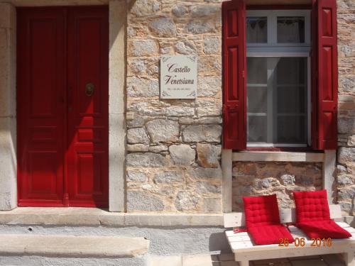 a bench with red pillows sitting in front of a building at Castello Venetsiana in Symi