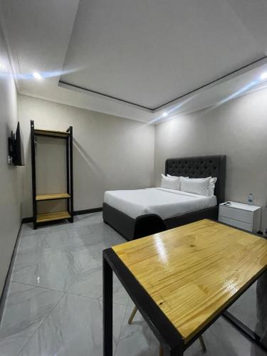 a bedroom with a bed and a wooden table at Palms & Pebbles Lodge in Lilongwe