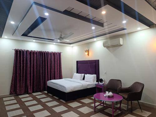a bedroom with a bed and a table and chairs at Emporia Hotel & Suites in Lahore