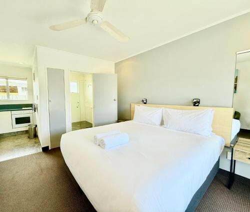 a bedroom with a large white bed with a ceiling at ASURE Fountain Resort Motel in Nelson