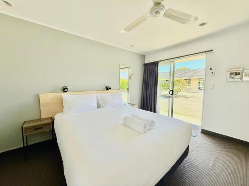 a bedroom with a large white bed and a window at ASURE Fountain Resort Motel in Nelson