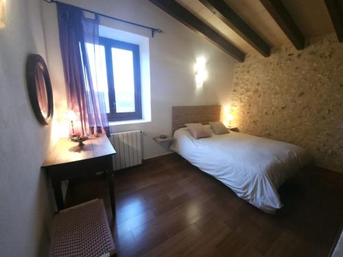 a bedroom with a bed and a desk and a window at Ca's Xibal·lí in Lloret de Vistalegre