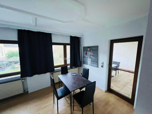 ein Esszimmer mit Tisch und Stühlen und Fenstern in der Unterkunft Mühlengarten by Relax Inn - Staffless with Self Check In & Free Parking in Nittel