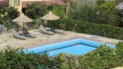 a swimming pool with chairs and umbrellas next to at Villa Medusa in Hersonissos