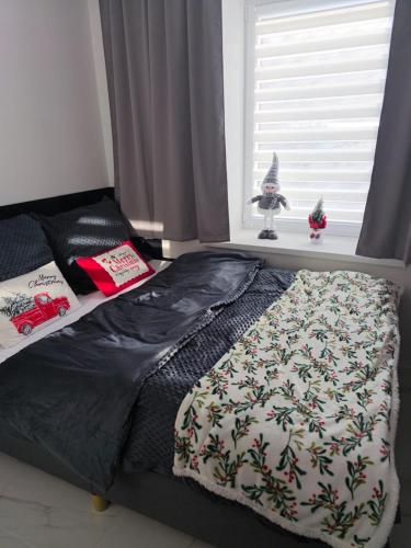 a bed with a blanket and a window with a christmas ornament at Blu Apartments in Jugów
