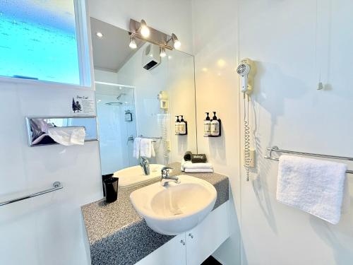 a white bathroom with a sink and a mirror at ASURE Fountain Resort Motel in Nelson
